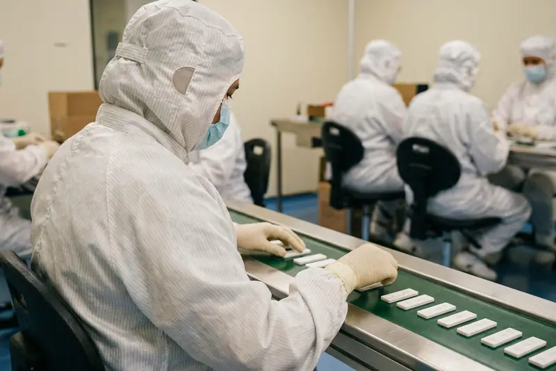 Un opérateur de trois quarts, visage non visible, conditionnant des cassettes de test en salle propre.