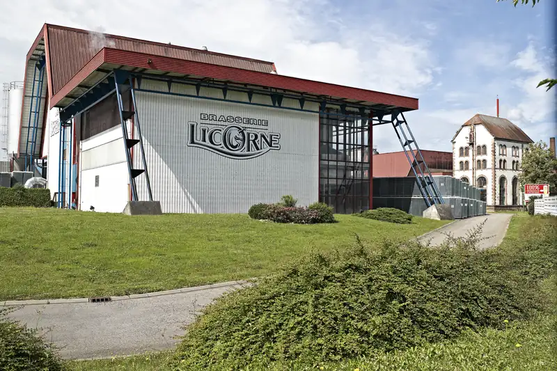 Le grand hall gris de la brasserie Licorne à Saverne, au nom de la marque, avec l'ancien bâtiment de brasserie à droite.