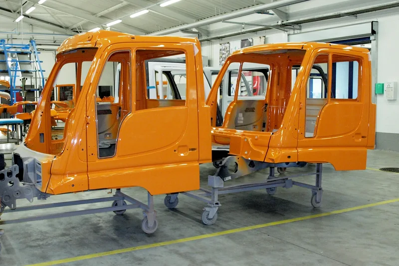Cabines orange de camions Unimog alignées dans un atelier lumineux de l'usine Mercedes-Benz de Molsheim, en 2015.
