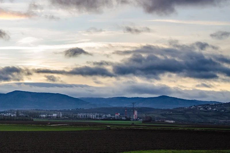 La zone industrielle d'Obernai au pied des Vosges : silos et cheminée rouge et blanche au bord d'une plaine agricole.