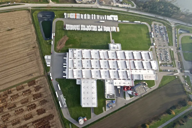 Vue aérienne d'une unité de l'usine SALM à Sélestat : grands halls blancs, parkings, camions et champs tout autour.