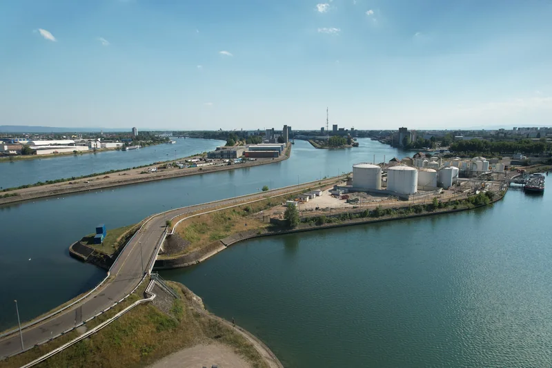 Vue aérienne des bassins du Port autonome de Strasbourg, avec les quais, les cuves de stockage et le Rhin au fond.