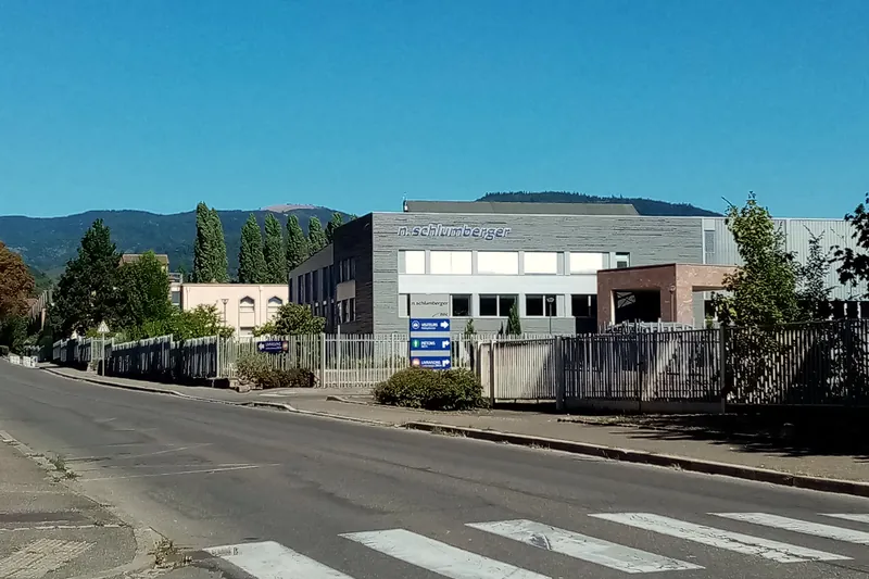 Le bâtiment N. Schlumberger, enseigne sur la façade, au bord de la route à Guebwiller, avec les Vosges en arrière-plan.