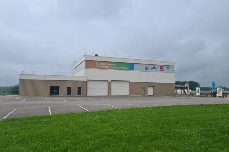 La centrale géothermique de Rittershoffen : bâtiment à panneaux sur la géothermie, vu depuis un parking enherbé, en 2023.
