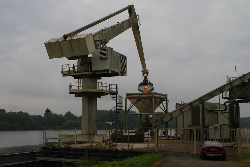 Grue de déchargement au bord du Rhin à Beinheim, bras plongé vers un bateau, avec une trémie et un convoyeur, en 2013.