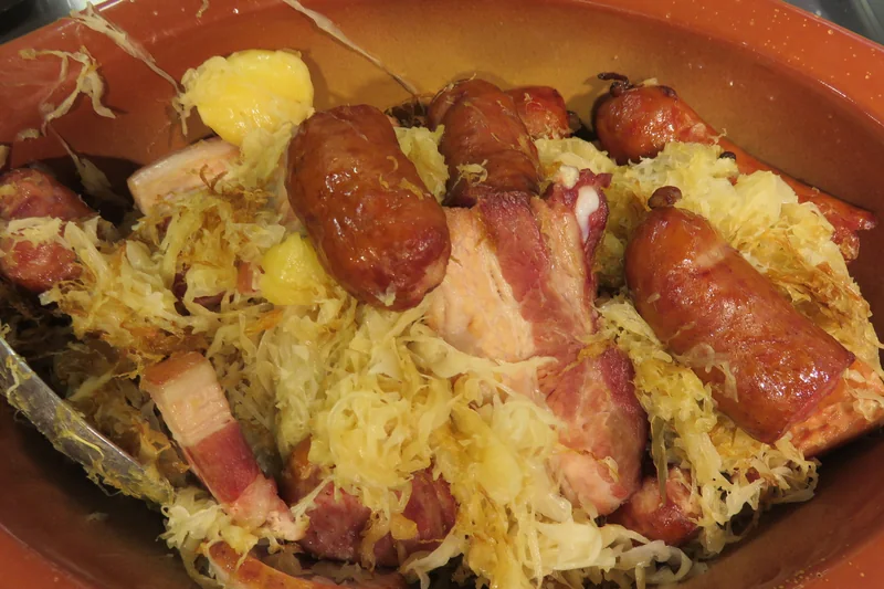 Choucroute alsacienne garnie dans un plat en terre cuite, avec saucisses, lard et pommes de terre, photographiée en 2015.