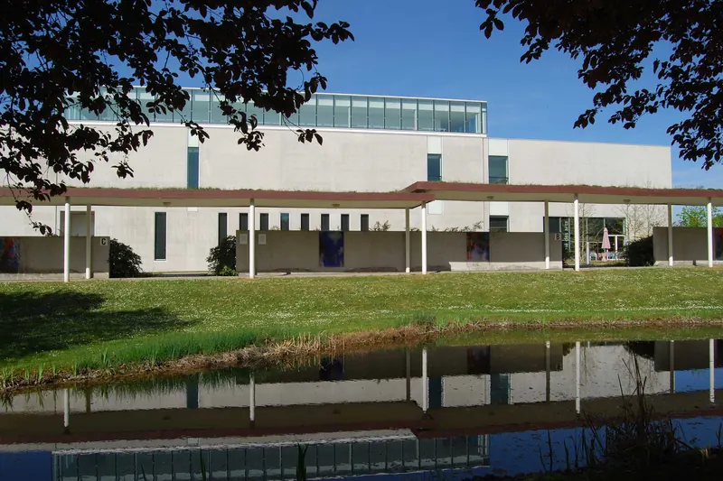 Le bâtiment du Musée Würth à Erstein derrière un bassin et les arbres du parc, façade claire aux grandes baies, en 2014.